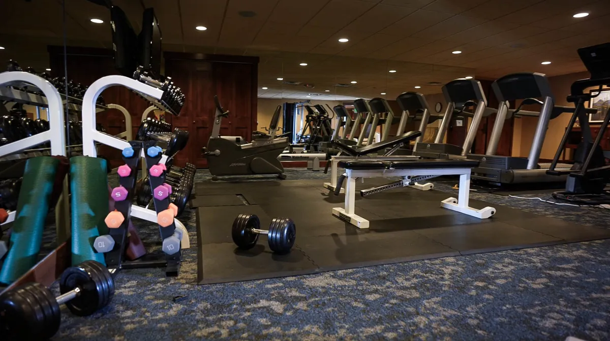 A modern fitness center featuring treadmills, a weight bench, and free weights. The bright space is equipped for both cardio and strength training, providing a motivating environment for wellness pursuits.