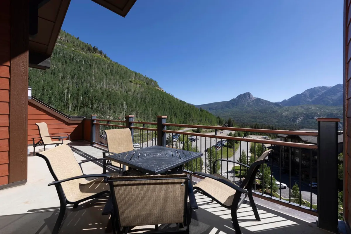 A tranquil exterior scene featuring an outdoor seating area with a table, set against a stunning mountain backdrop. The area is ideal for relaxing or socializing after a day on the slopes and offers sunrise or stargazing opportunities in a serene alpine setting.