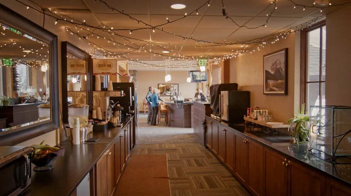 This welcoming interior showcases a coffee station and bar area adorned with decorative lights and framed artwork, suggesting a space for social gatherings, casual dining, and enjoying time with friends or family.